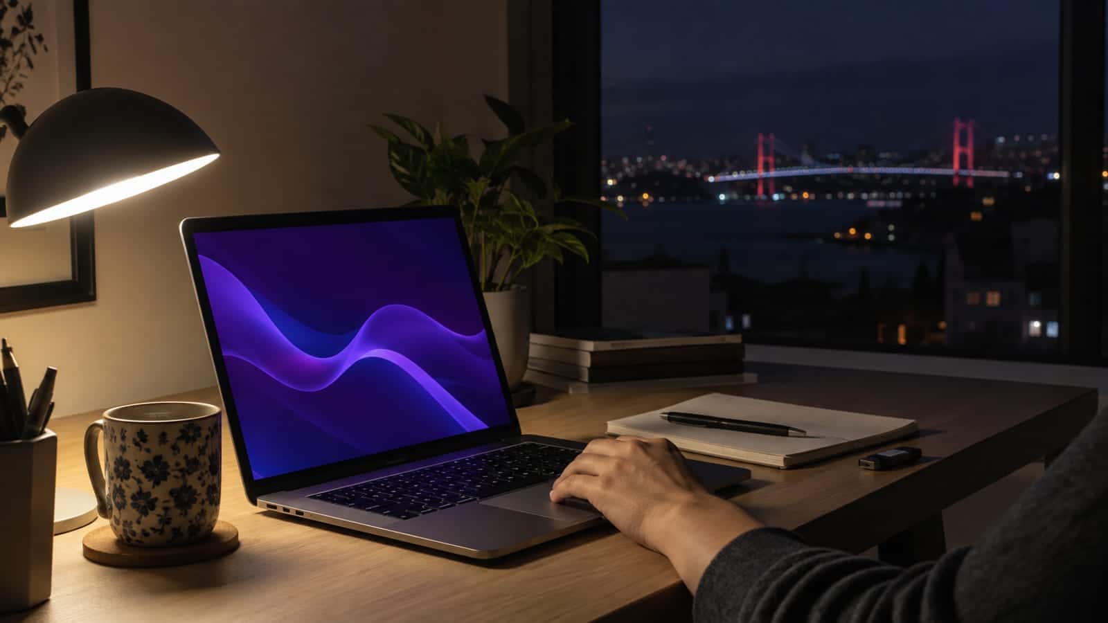 Gece karanlığında masa lambası ışığında açık duran dizüstü bilgisayar, yanında not defteri ve USB bellek
